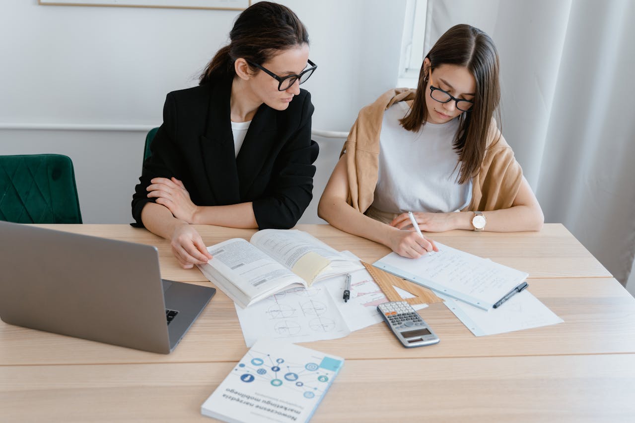 Female tutor teaching maths to a teenager at a desk.