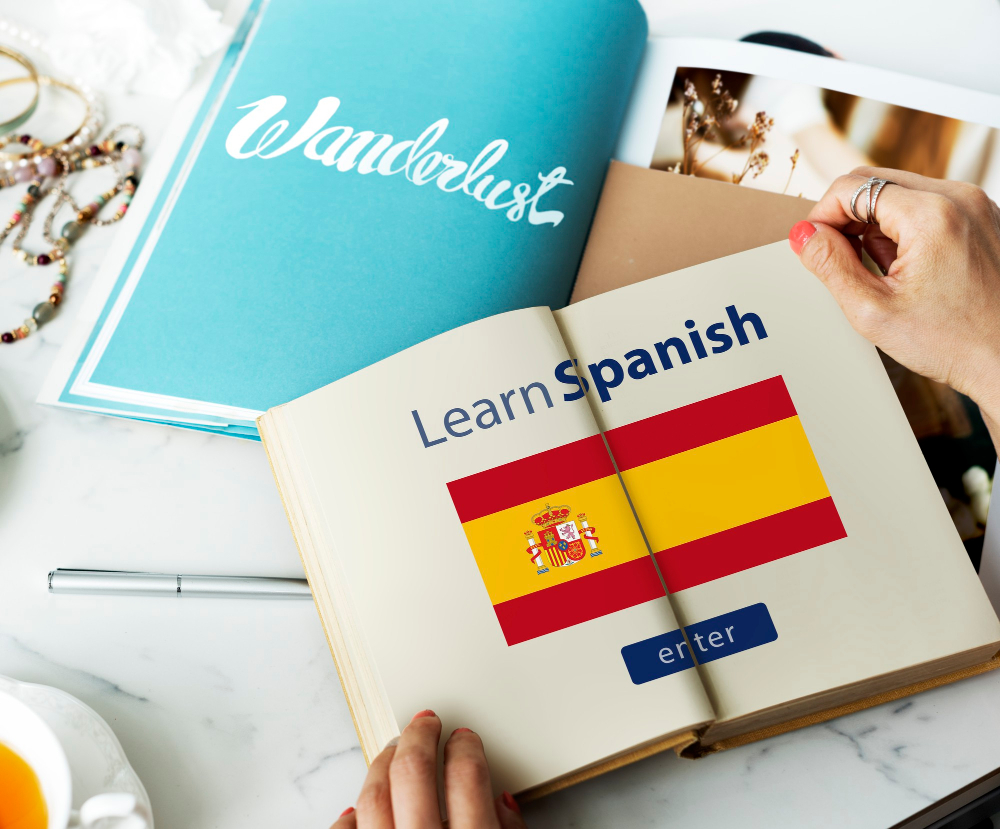 An open book on a table showing pages with the Spanish flag and the words “Learn Spanish enter”.