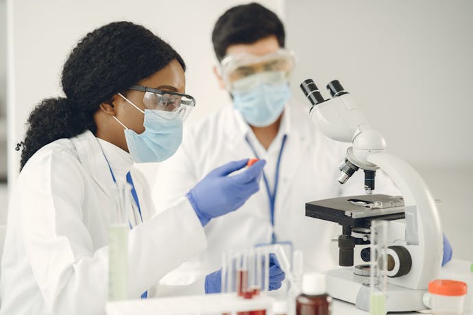 A female student using lab equipment while a teacher watches in a science classroom.