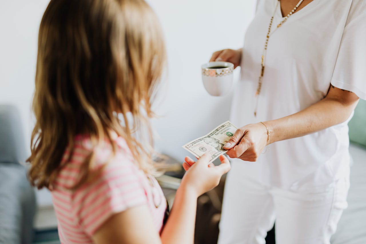 A mother giving her young daughter pocket money